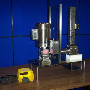 The Gear and Rack Feeder, Cortical Bone Mill is sitting on a table in front of a blue wall.