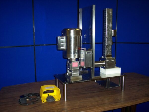 The Gear and Rack Feeder, Cortical Bone Mill is sitting on a table in front of a blue wall.